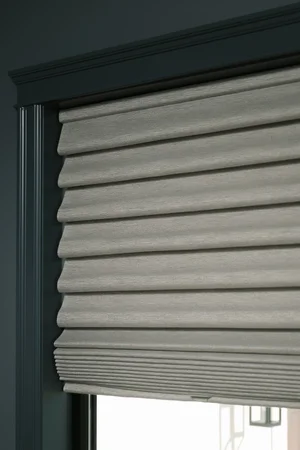 Grey indoor roller shades that are in a bedroom window.