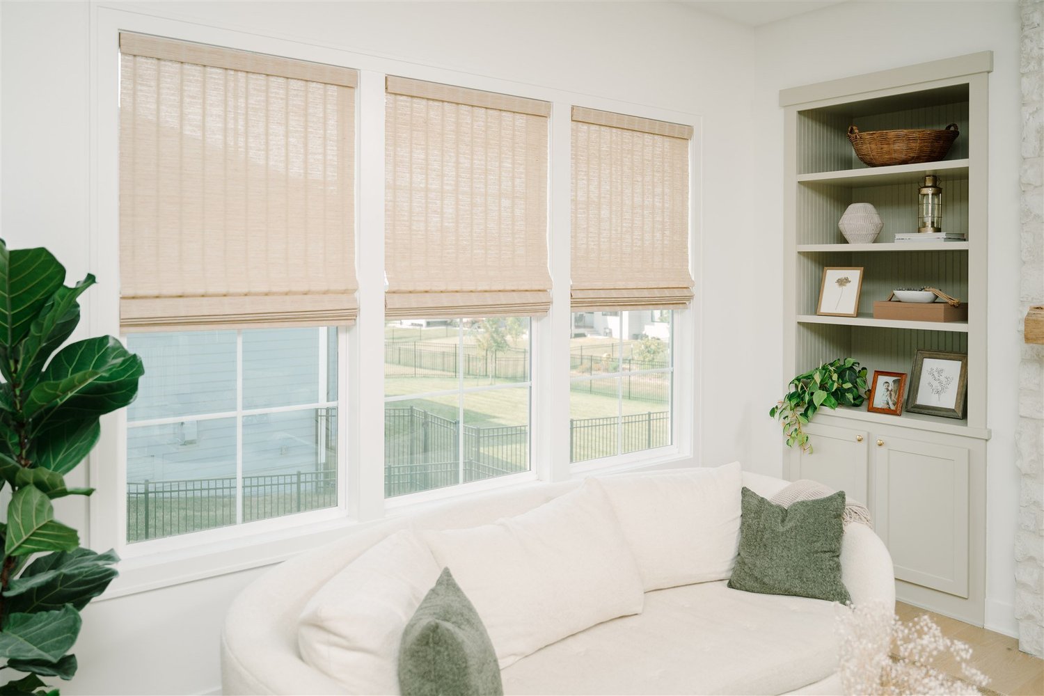 Indoor roller shades behind a couch and bookshelf.