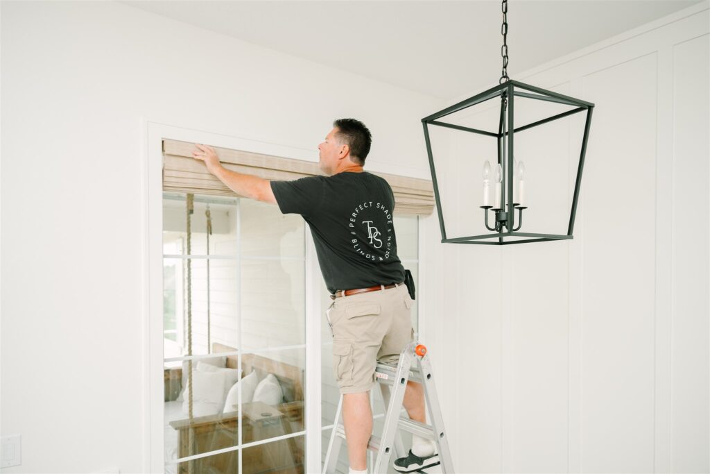 Close view of an installer adjusting the edge of a woven wood window shade.
